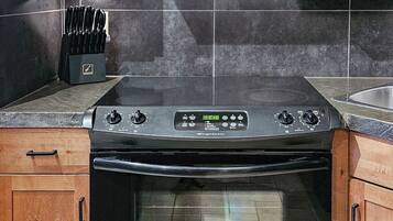 A kitchen with a black stove, wooden cabinets, and a knife block.