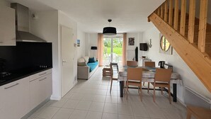 Une cuisine moderne avec un coin repas, un escalier en bois et une vue sur l’extérieur.