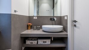 A modern bathroom with a large mirror, a white sink, and storage baskets under the counter.