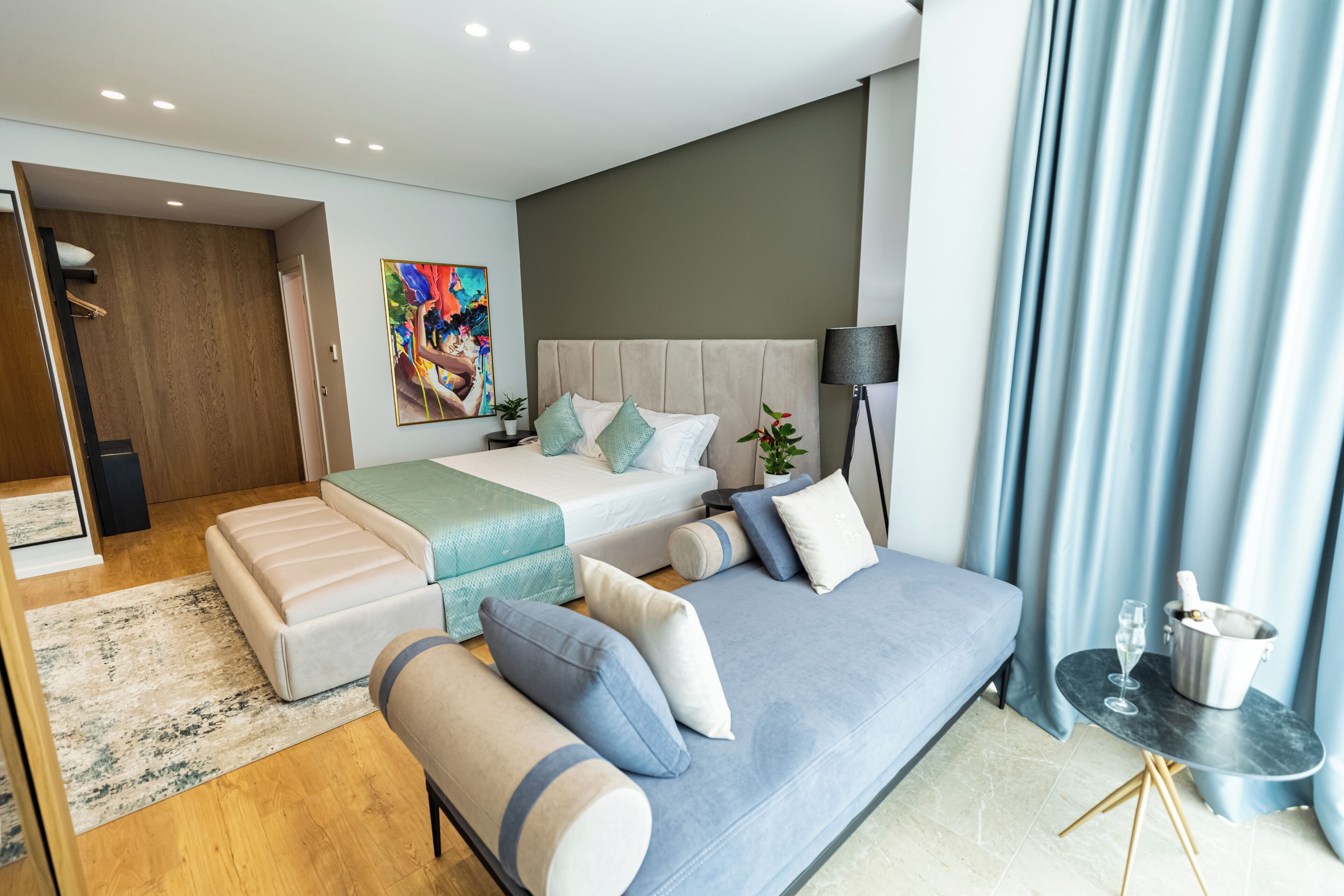 Um quarto moderno com cama, sofá, mesa de cabeceira e um quadro na parede.
