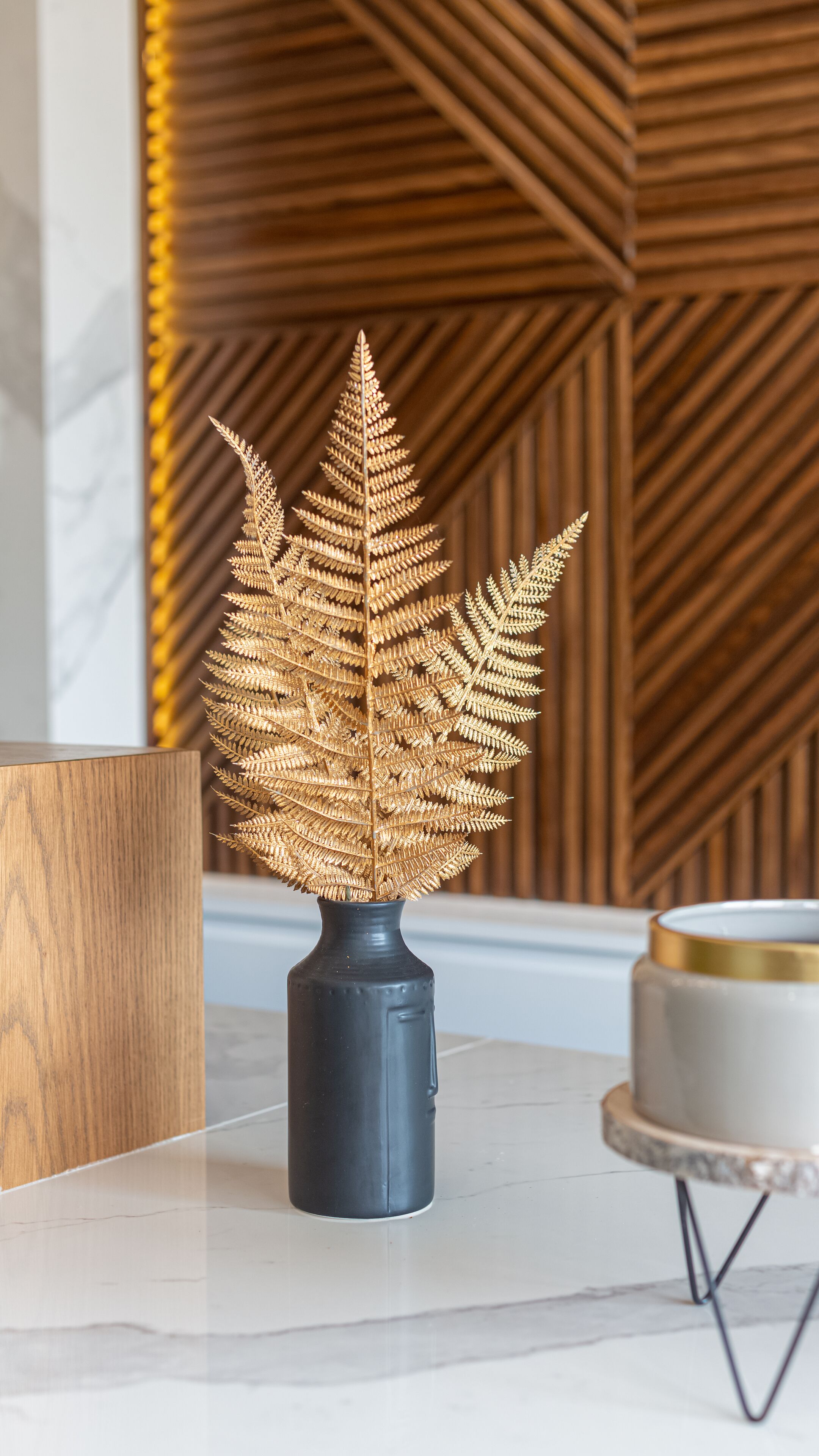 Un helecho decorativo en una maceta sobre una mesa de mármol.