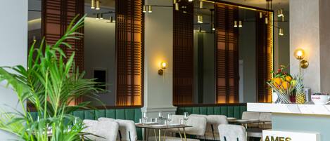 Un hall d’hôtel comprenant un comptoir d’accueil, un espace salon et de grandes fenêtres avec des persiennes en bois.