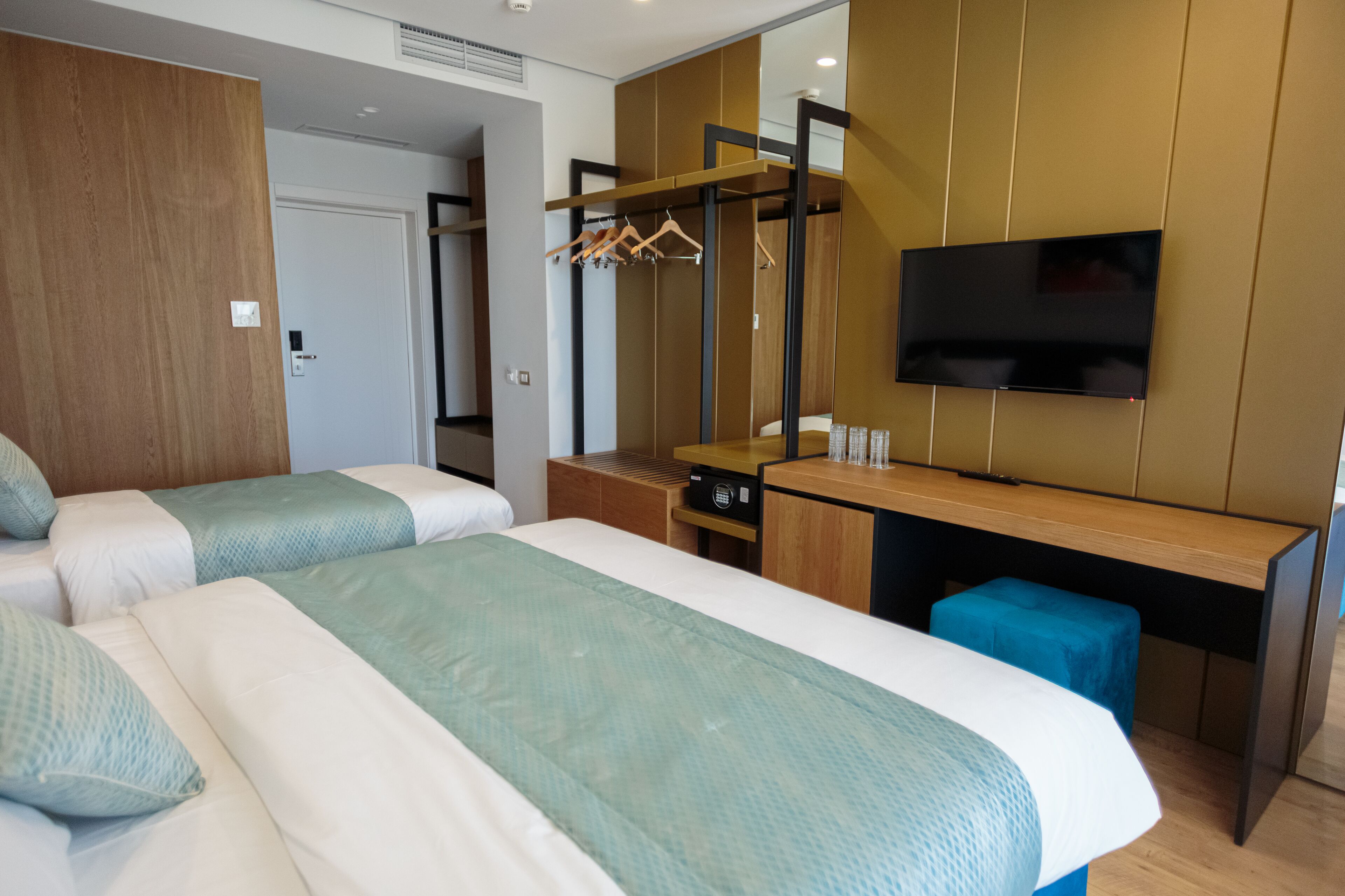 Une chambre d’hôtel avec deux lits, un bureau, une télévision et une armoire.