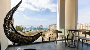 A balcony with a hanging chair, a table, and chairs.