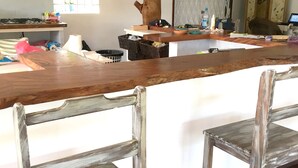 Cozinha com ilha de madeira, duas cadeiras rústicas, janela com grades e porta decorada com um coração.