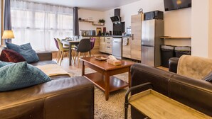 Un espacio habitable pequeño con sofá, mesa de comedor y kitchenette.