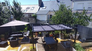 Una terraza de madera con mobiliario exterior y plantas en macetas.