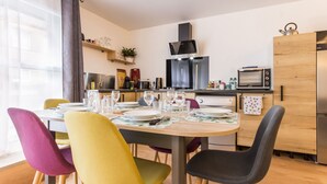 Una cocina moderna con una mesa de comedor para cuatro personas, sillas coloridas y un horno empotrado.