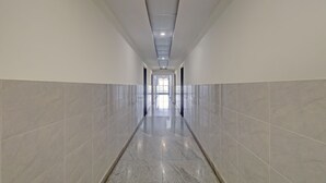 Un long couloir étroit, doté d’un sol et de murs carrelés, qui mène à un espace lumineux et ouvert au bout.