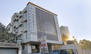 Un immeuble à plusieurs étages, sur lequel on peut lire l’inscription « SAI SUITES INN », indiquant la présence de chambres de catégorie supérieure.