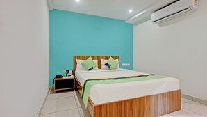 Une chambre d’hôtel moderne avec un cadre de lit en bois, des murs de couleur turquoise et un plafond blanc.