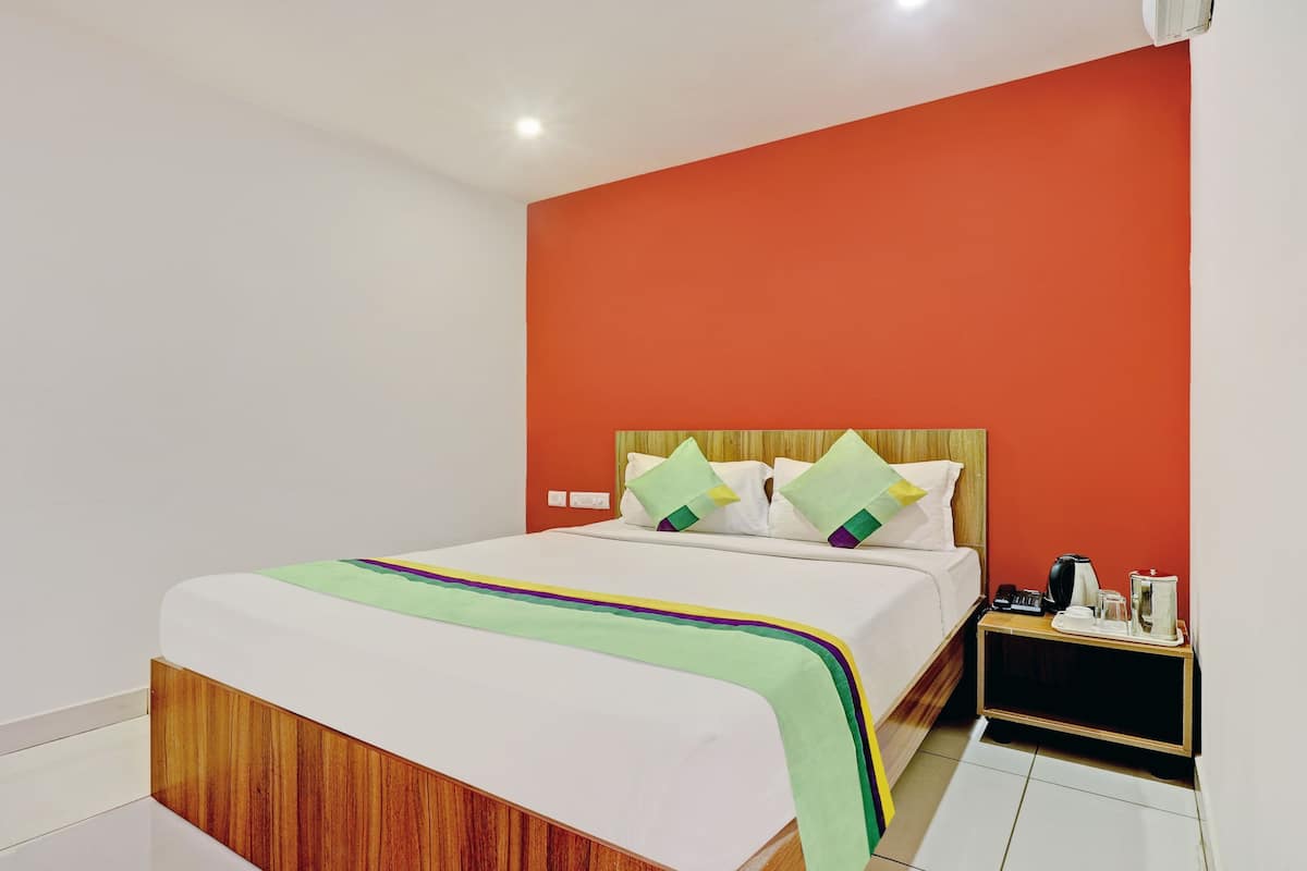 A hotel room with a bed, a nightstand, and a red accent wall.