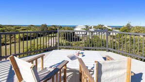 A terrace with a view of the sea, featuring a table with chairs and a cup. - Ideal Beach Family Getaway with Ocean Views (Noosa North Shore)