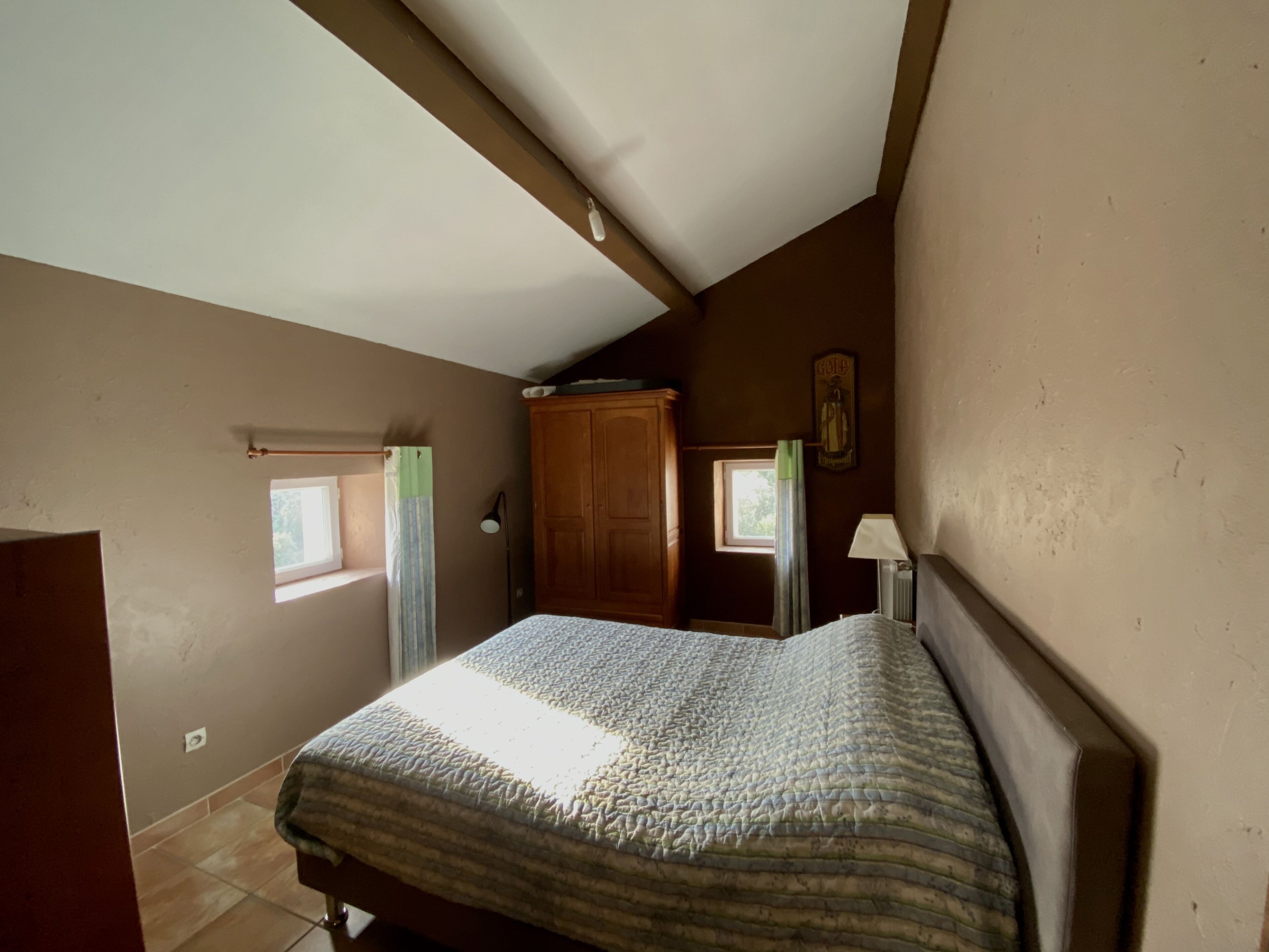 Une chambre à coucher avec un lit, une armoire, une fenêtre et un radiateur.