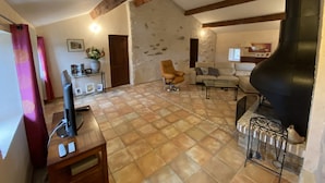 Ein geräumiges Wohnzimmer mit Kamin, einer Couch, einem Couchtisch und einem Fernseher auf einem Holzboden.