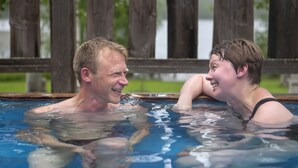 Two people in a swimming pool with a wooden fence in the background. - Taulun Kartano (Toivakka)