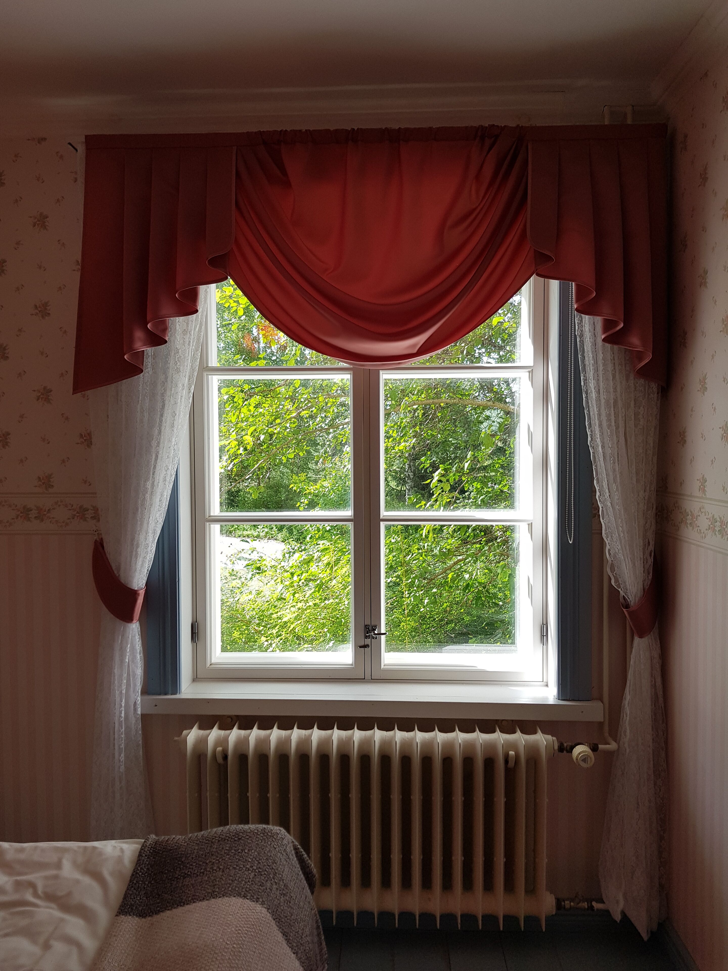 A room with a window, a radiator, and a bed.