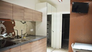A modern kitchen with wooden cabinets, a stainless steel sink, and a built-in oven. - Invalides•Tour Eiffel | Charming flat Paris Centre (Paris)