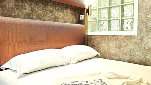 A hotel room with a textured headboard, a bed with white linens, a window with green frames, and a decorative pillow. - Invalides•Tour Eiffel | Charming flat Paris Centre (Paris)