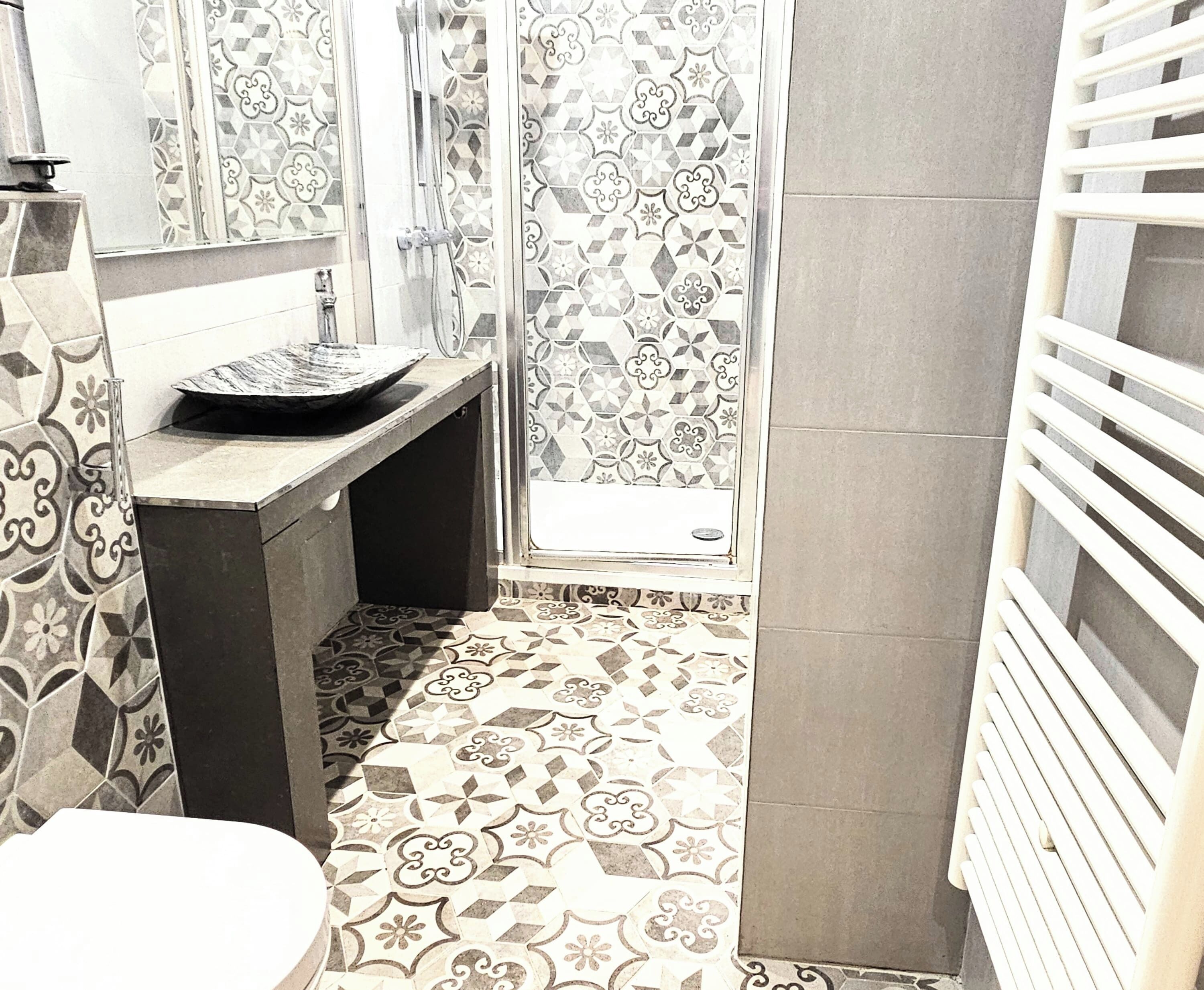 Une salle de bain avec des carreaux décorés, un lavabo et un espace douche.