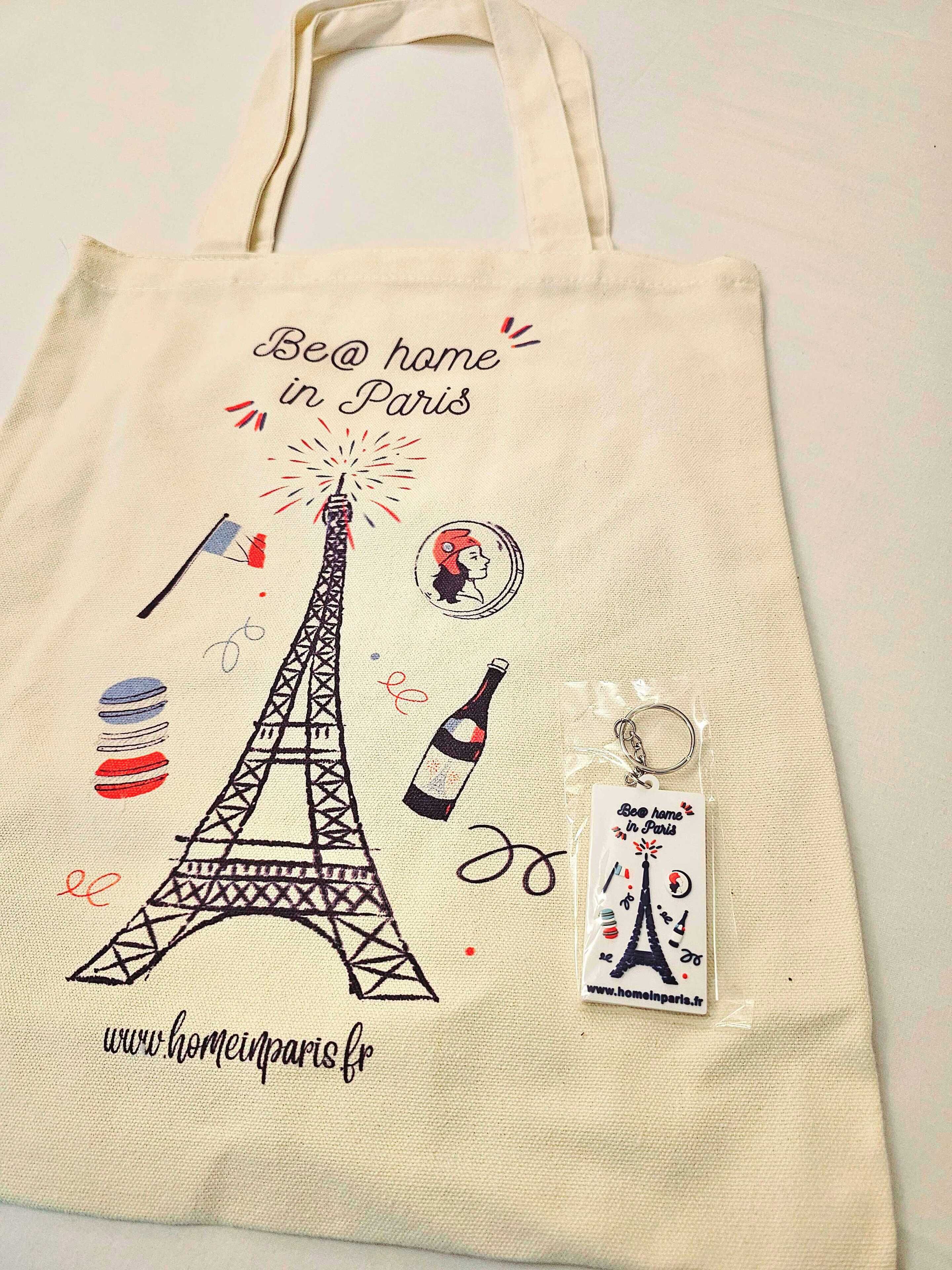 Una bolsa de tela con la Torre Eiffel e ilustraciones relacionadas con París, incluyendo una botella de vino y un llavero.