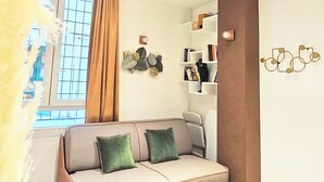 A living room with a sofa, a bookshelf, and decorative wall art. - Invalides•Tour Eiffel | Charming flat Paris Centre (Paris)