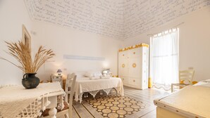 Une pièce avec un lit, une table sur laquelle se trouve un vase, et une chaise.