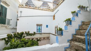 A narrow alleyway with a white building, blue-painted steps, and potted plants. - Camera Fiori Di Pesco - Racale (Racale)