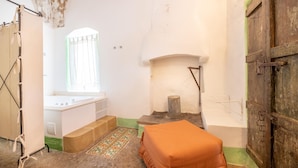 A bathroom with a bathtub, a window, a fireplace, and a wooden door. - Camera Del Focolare - Racale (Racale)