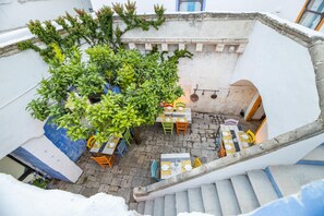 Un patio con escaleras, zona de estar al aire libre y un árbol.