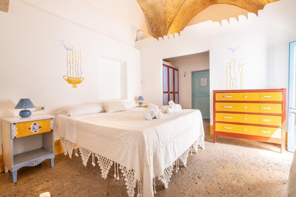 Un dormitorio con cama, mesita de noche, cómoda y una puerta que da a otra habitación.