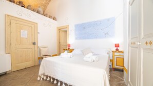 Une chambre à coucher avec un grand lit, une porte en bois, une petite table avec une lampe et un mur agrémenté d’éléments décoratifs.