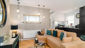 Ein modernes Wohnzimmer mit Sofa, Couchtisch und Essbereich mit Lampe.