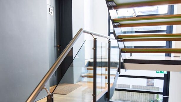 A modern interior with a glass railing, wooden flooring, and a staircase with a metal handrail. - Spacious 2 Bd Apt w/Fast Wifi+CableTV+Audio System (Cardiff)