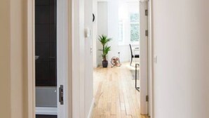 A hallway with wooden flooring, white walls, and a ceiling light. - Superb Modern 1 Bedroom Apt | Cocoon Dbl Sofa Bed (Cardiff)