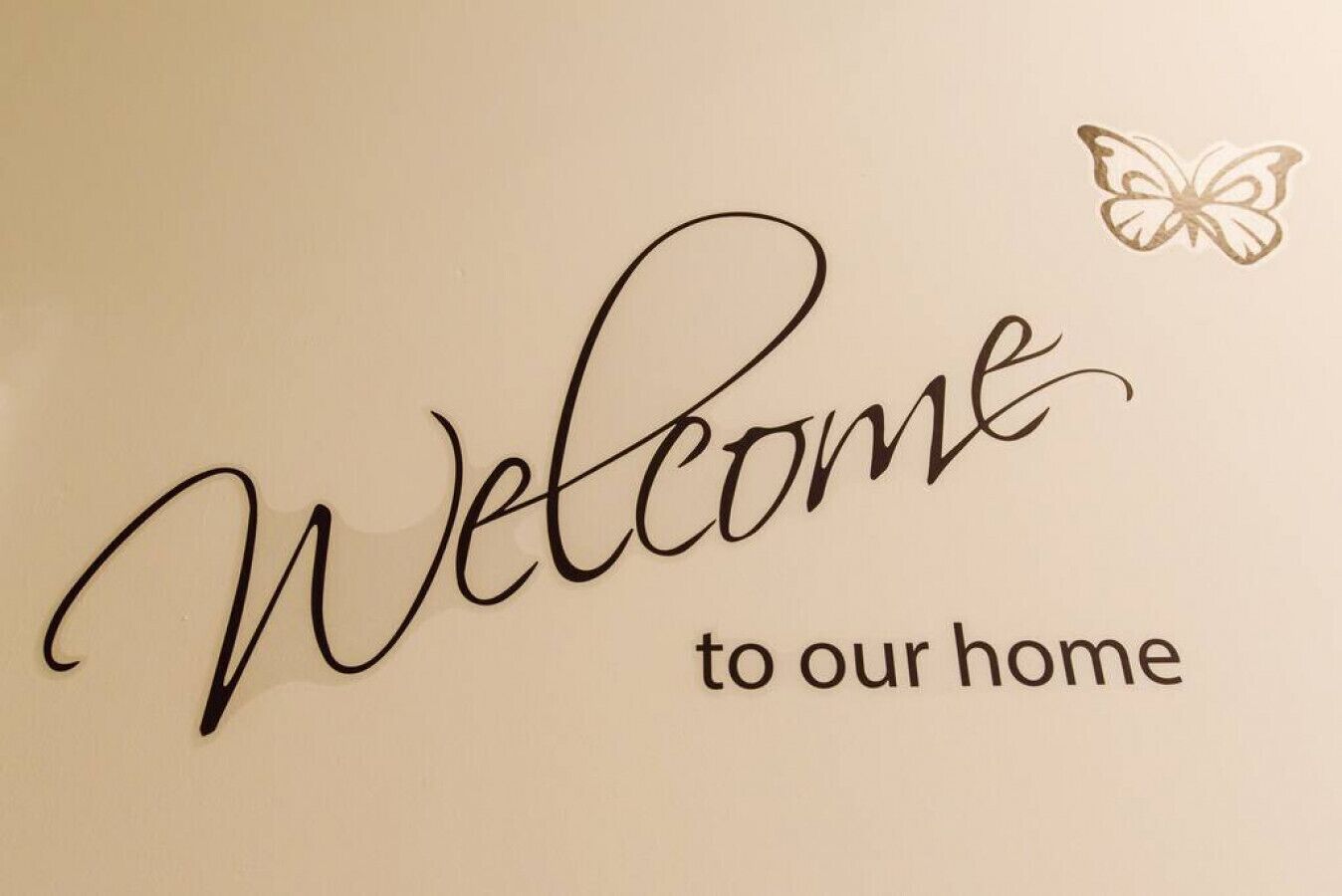 Un mur orné des mots « Bienvenue chez nous » et d’une décoration en forme de papillon.