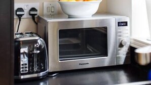 A kitchen with a microwave, toaster, and a bowl of fruit on the counter. - Superb Modern 1 Bedroom Apt | Cocoon Dbl Sofa Bed (Cardiff)