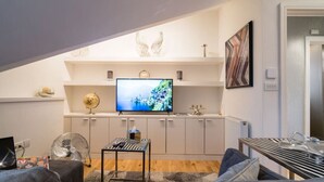 Een moderne woonkamer met een flatscreen televisie, een klein tafeltje en een bank.