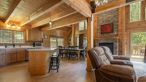 A spacious living area with a fireplace, wooden flooring, and a dining area with a large table and chairs.