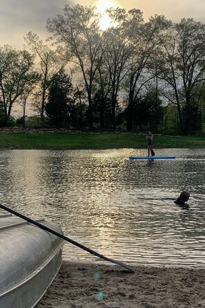A person paddleboarding on a calm body of water with trees in the background.
