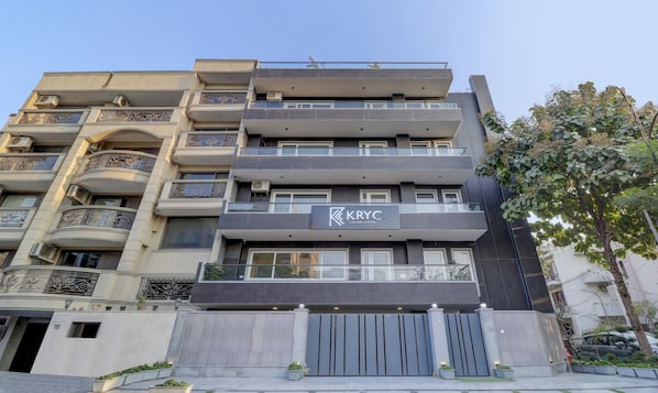 A multi-story building with balconies, air conditioning units, and a gated entrance.