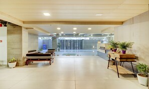 A reception area with a reception desk, seating area with cushioned chairs, and potted plants.