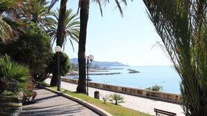 A paved walkway with benches, palm trees, and a view of the sea. - kaDevi Holiday home -full center, private garage and bikes (Sanremo)