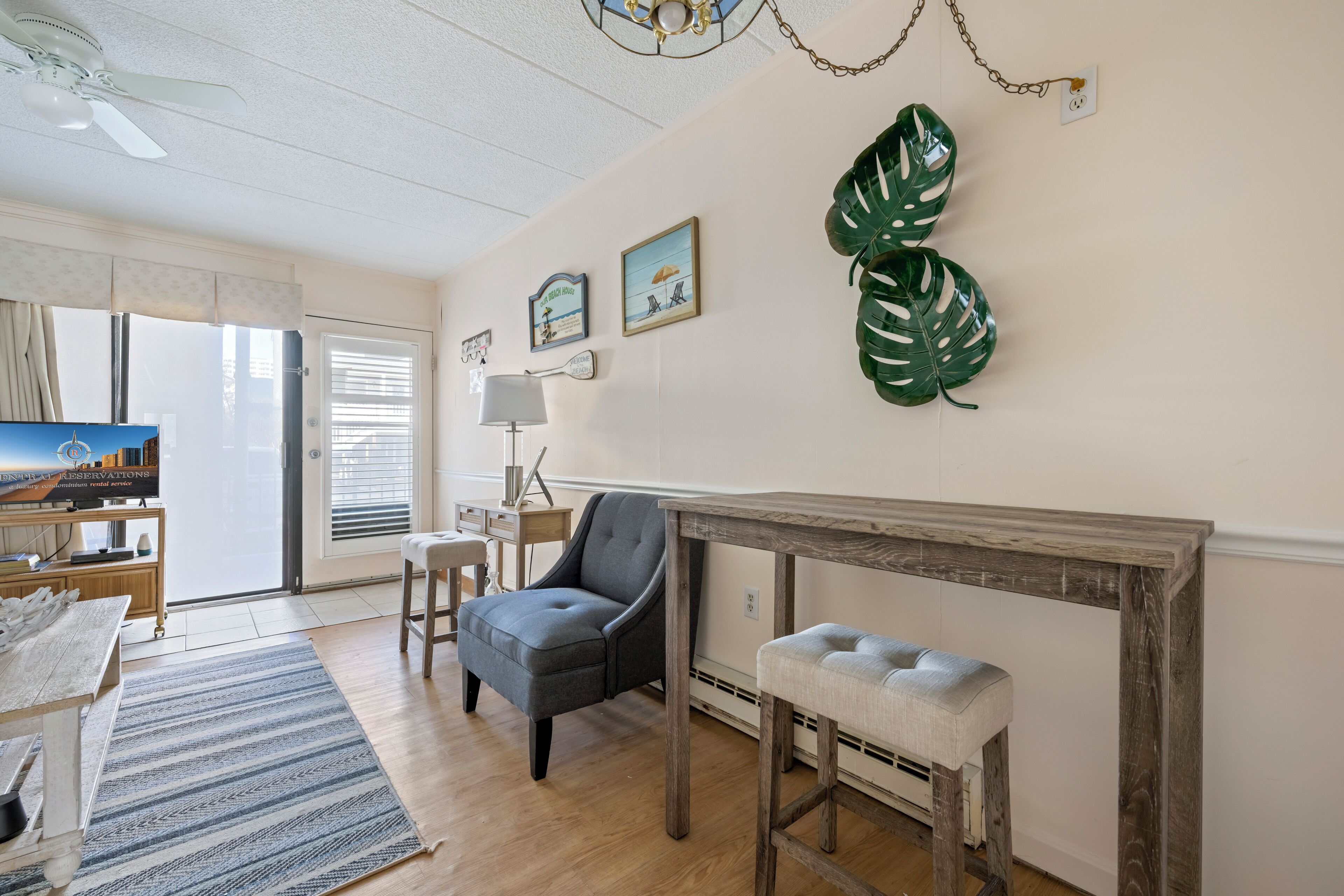 Una sala de estar con una mesa de madera, un sillón gris, un banco y una chimenea.