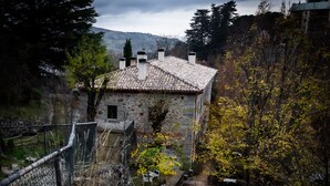 A stone building with a tiled roof, surrounded by trees and a stone wall. - Posada Peña Pintada by Vivere Stays (Cercedilla)