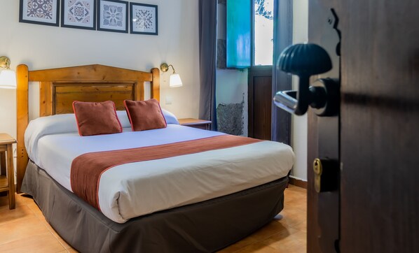 A neatly made bed with a wooden headboard, a bedside table, and a nightstand. - Posada Peña Pintada by Vivere Stays (Cercedilla)