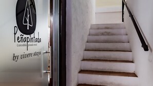 A staircase with white walls and a glass door with a logo. - Posada Peña Pintada by Vivere Stays (Cercedilla)