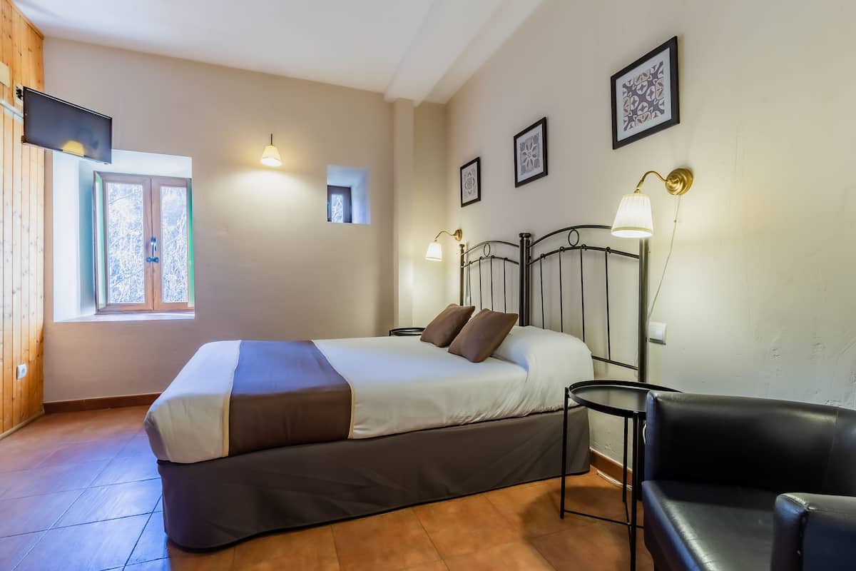Une chambre à coucher avec un lit, une chaise, une télévision et une fenêtre.