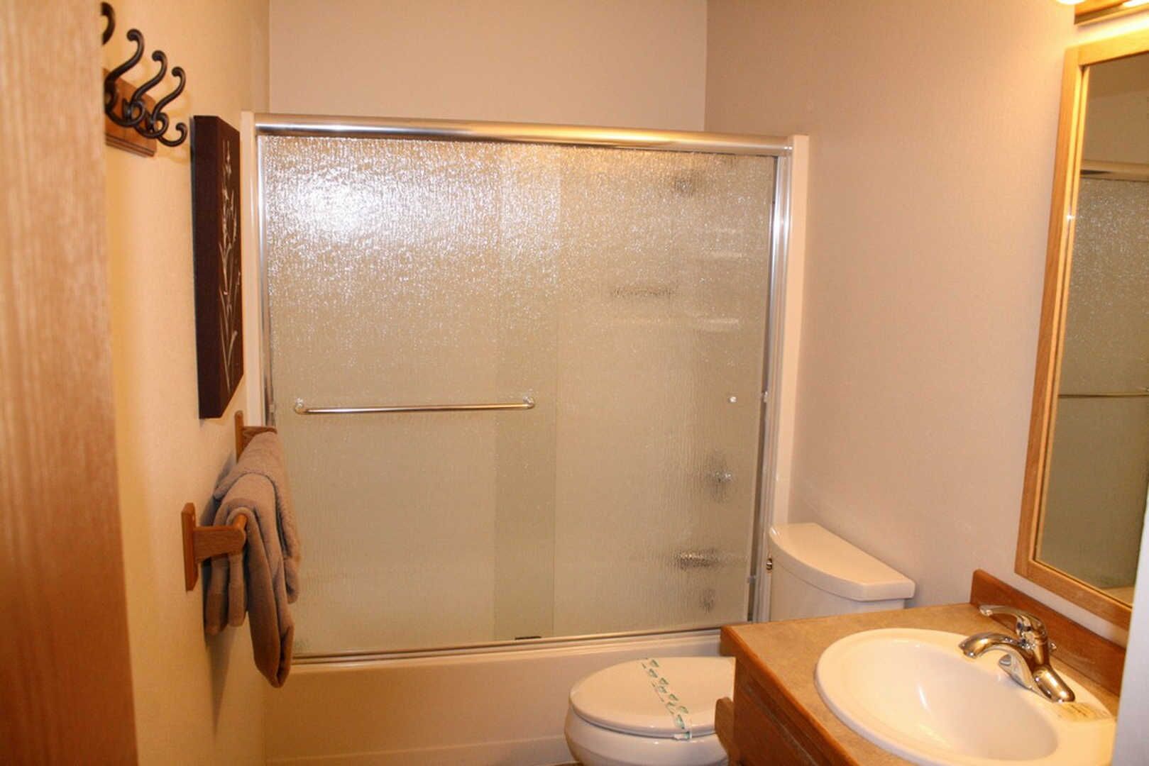 Un bagno con doccia vetro, un water e un lavandino con specchio sopra.