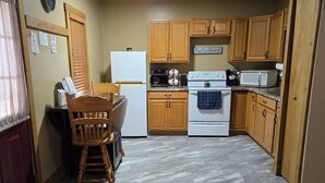 A compact kitchen with wooden cabinets, a white refrigerator, a stove, and a microwave.